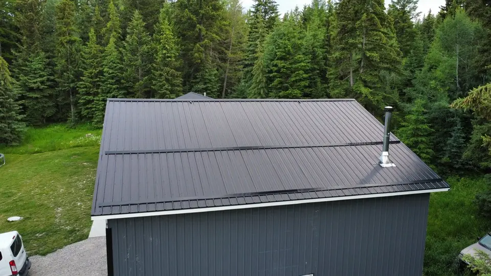 Aerial drone view of a shingle roof surrounded by trees in the Flathead Valley